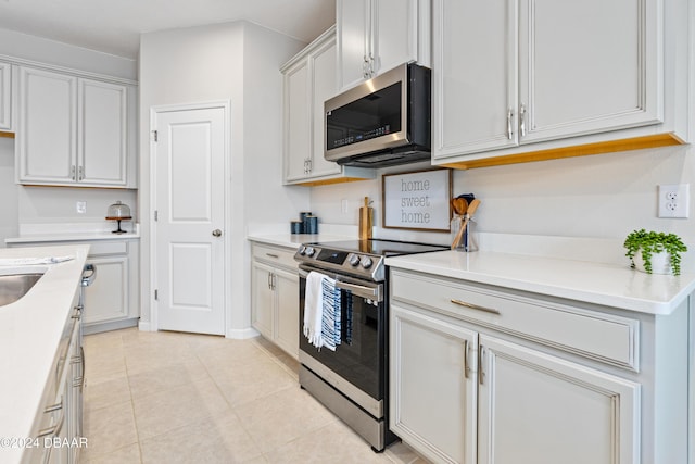 kitchen with light tile patterned flooring, white cabinetry, and stainless steel appliances