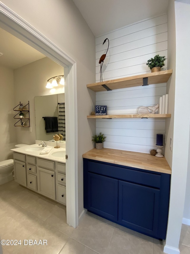 bathroom with toilet, vanity, and tile patterned floors