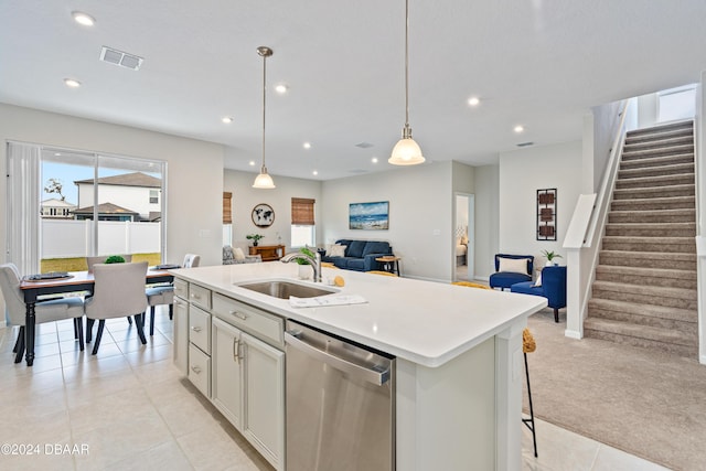 kitchen with light colored carpet, sink, decorative light fixtures, dishwasher, and an island with sink