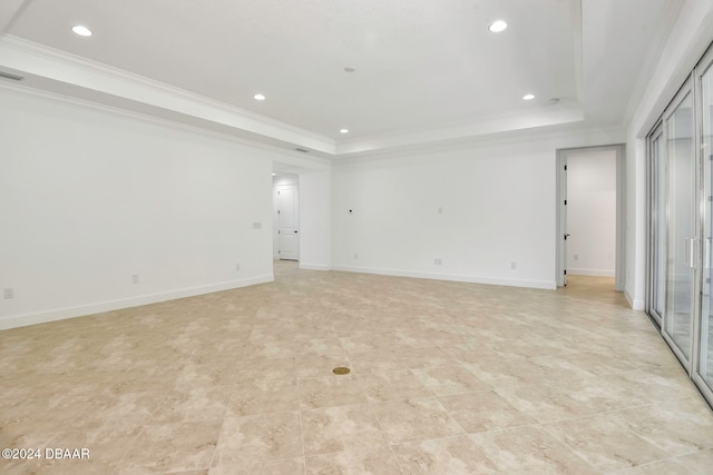 unfurnished room featuring a raised ceiling, ornamental molding, and a wealth of natural light