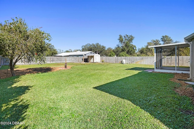 view of yard featuring a sunroom and a storage shed