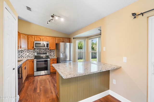 kitchen with light stone counters, kitchen peninsula, stainless steel appliances, and dark wood-type flooring