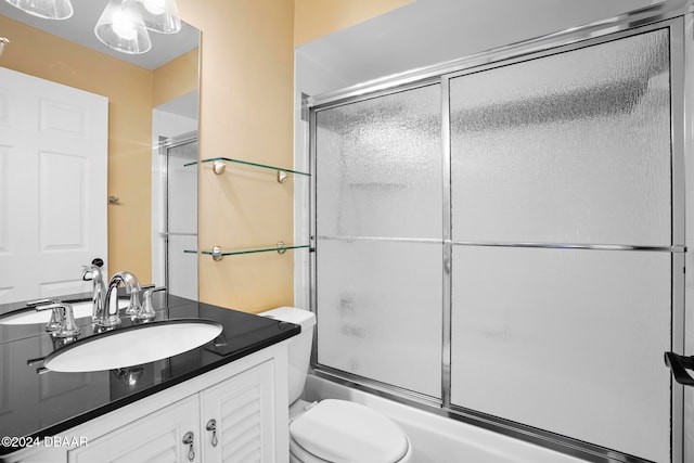 full bathroom featuring vanity, bath / shower combo with glass door, and toilet