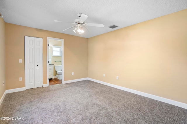 unfurnished bedroom with ensuite bath, ceiling fan, carpet floors, a textured ceiling, and a closet