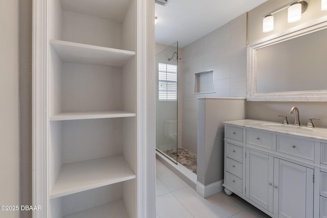 bathroom with tiled shower, tile patterned flooring, and vanity