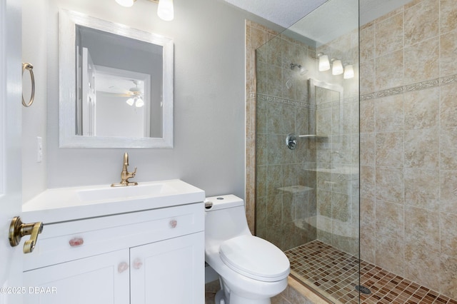 bathroom with tiled shower, vanity, and toilet