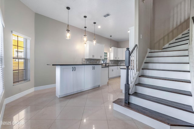 kitchen with hanging light fixtures, white cabinetry, light tile patterned floors, and decorative backsplash