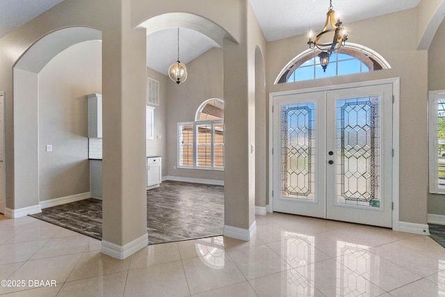 entrance foyer featuring light tile patterned floors, a chandelier, a high ceiling, and a wealth of natural light