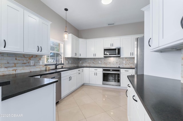 kitchen featuring white cabinetry, hanging light fixtures, stainless steel appliances, sink, and decorative backsplash