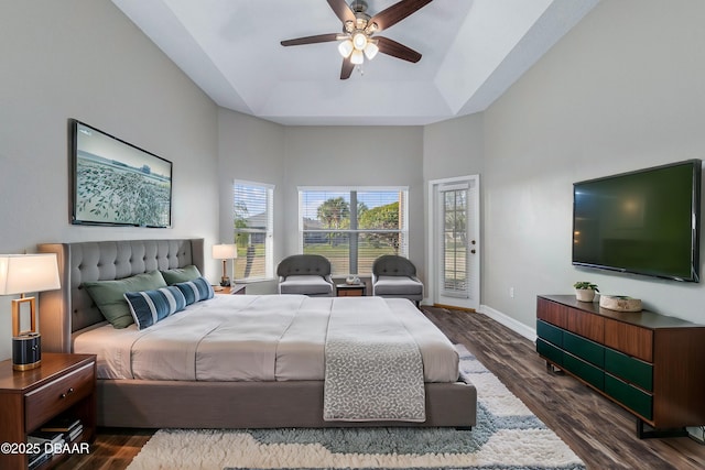 bedroom with a raised ceiling, a high ceiling, access to outside, and dark hardwood / wood-style floors