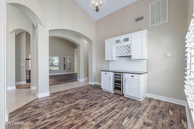 bar featuring wine cooler, high vaulted ceiling, white cabinets, dark hardwood / wood-style floors, and decorative backsplash