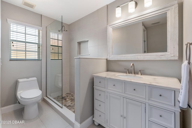 bathroom featuring vanity, tiled shower, toilet, and tile patterned floors