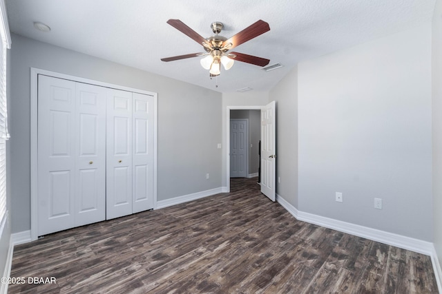 unfurnished bedroom featuring ceiling fan, a closet, dark wood-type flooring, and a textured ceiling