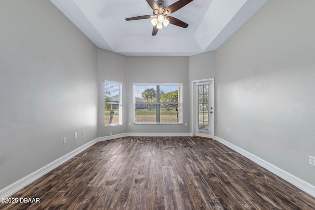 empty room featuring a tray ceiling, ceiling fan, and dark hardwood / wood-style floors