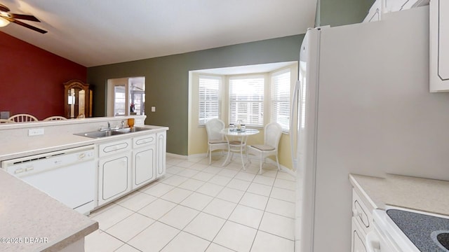 kitchen featuring light tile patterned floors, light countertops, white cabinets, a sink, and white appliances