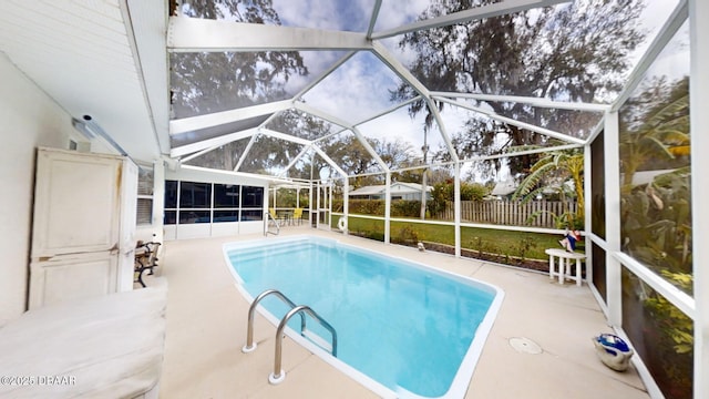 view of pool featuring glass enclosure, fence, a fenced in pool, and a patio