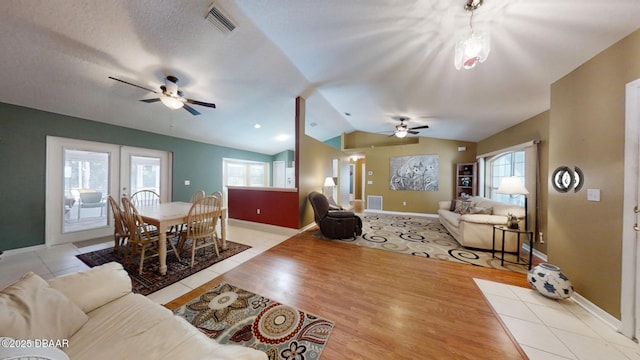 living area featuring lofted ceiling, light wood-type flooring, visible vents, and a ceiling fan