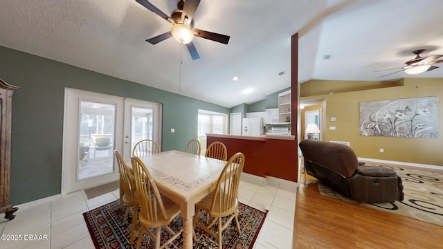 dining space featuring light tile patterned floors, baseboards, a ceiling fan, lofted ceiling, and a textured ceiling