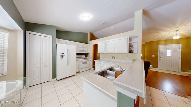 kitchen featuring light countertops, white cabinets, vaulted ceiling, a sink, and white appliances