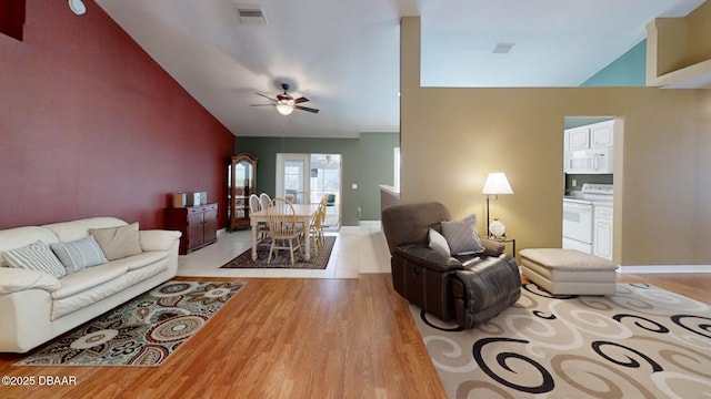 living area with lofted ceiling, visible vents, and wood finished floors