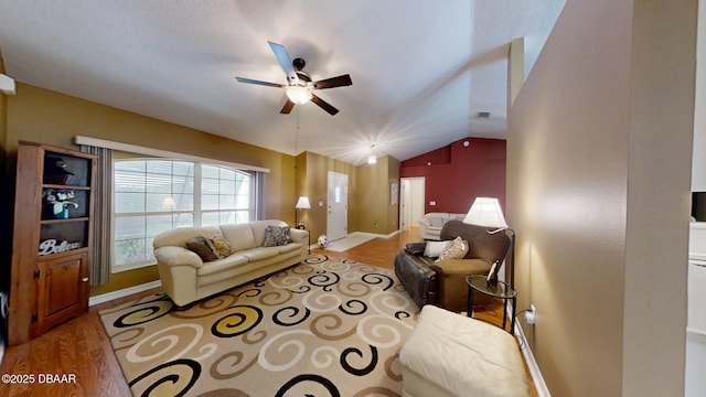 living area featuring vaulted ceiling, ceiling fan, wood finished floors, and baseboards