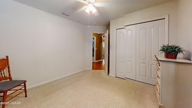 living area featuring baseboards, ceiling fan, light carpet, and visible vents