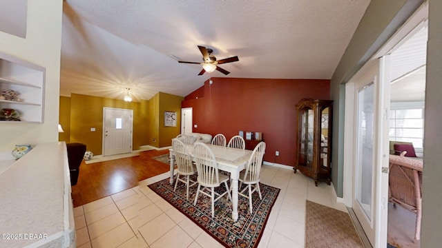 dining area featuring lofted ceiling, light tile patterned flooring, ceiling fan, a textured ceiling, and baseboards