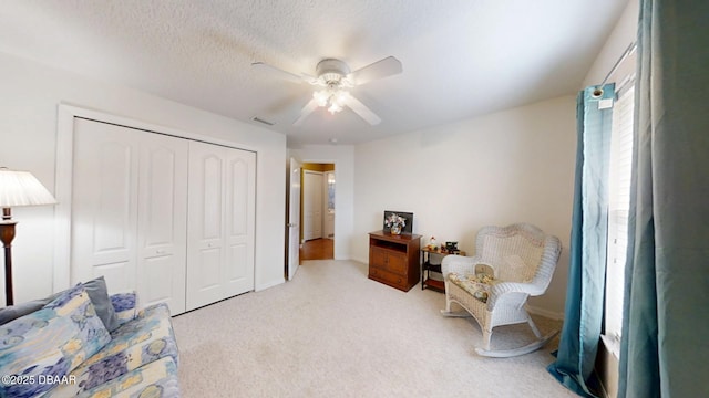 sitting room featuring a ceiling fan, carpet, visible vents, and a textured ceiling