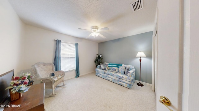 sitting room featuring ceiling fan, a textured ceiling, visible vents, baseboards, and carpet