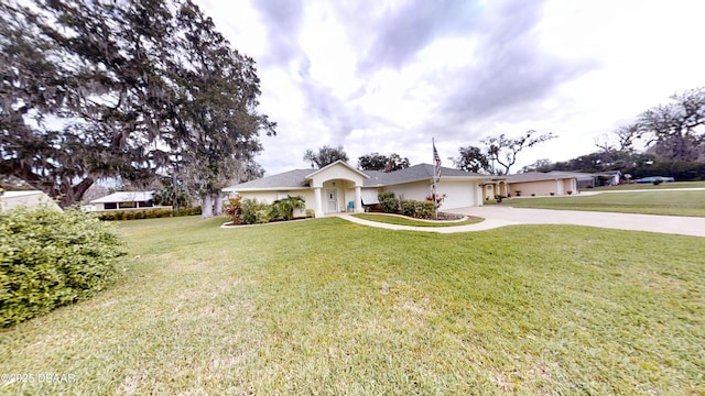 ranch-style home with a front yard, concrete driveway, an attached garage, and stucco siding