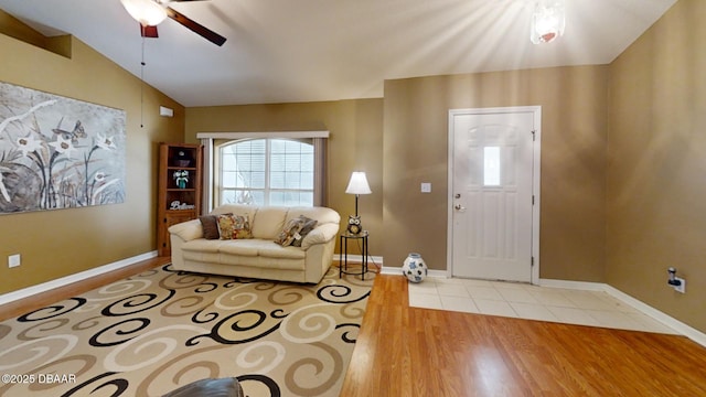 living area with light wood-style floors, vaulted ceiling, baseboards, and a ceiling fan