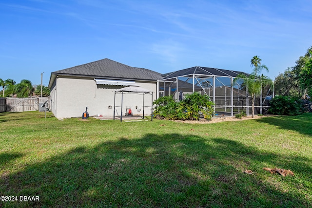 back of house featuring glass enclosure, a patio area, and a lawn