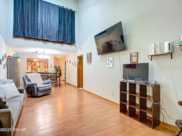 living room with an inviting chandelier, hardwood / wood-style floors, and a high ceiling