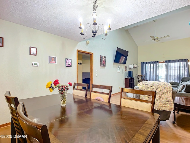 dining area with vaulted ceiling, ceiling fan with notable chandelier, hardwood / wood-style floors, and a textured ceiling