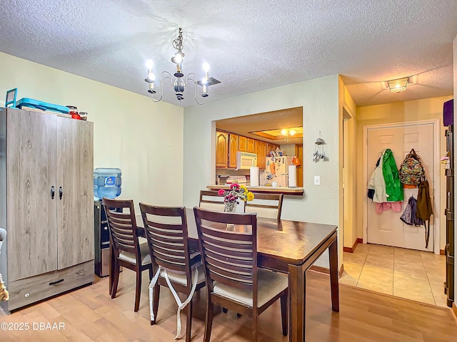 dining space featuring light hardwood / wood-style floors, a textured ceiling, and a notable chandelier