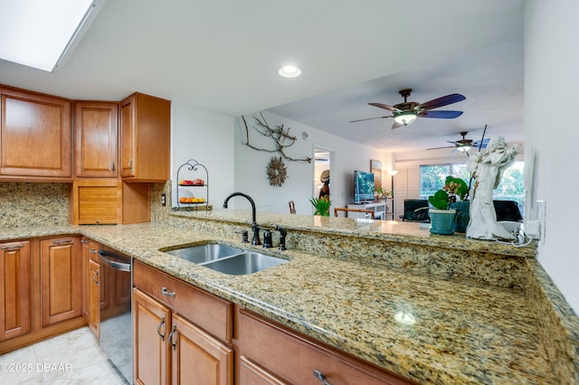 kitchen with tasteful backsplash, dishwasher, sink, light stone counters, and kitchen peninsula