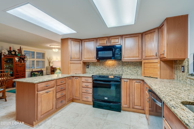 kitchen featuring tasteful backsplash, light stone countertops, kitchen peninsula, and black appliances