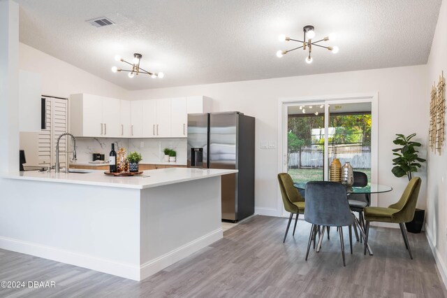 kitchen featuring white cabinetry, an inviting chandelier, stainless steel fridge with ice dispenser, lofted ceiling, and light wood-type flooring