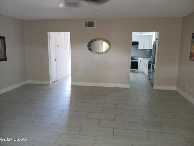 empty room with ceiling fan and light tile patterned floors