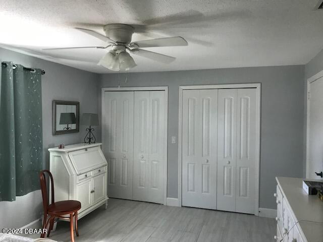 bedroom featuring a textured ceiling, ceiling fan, and two closets