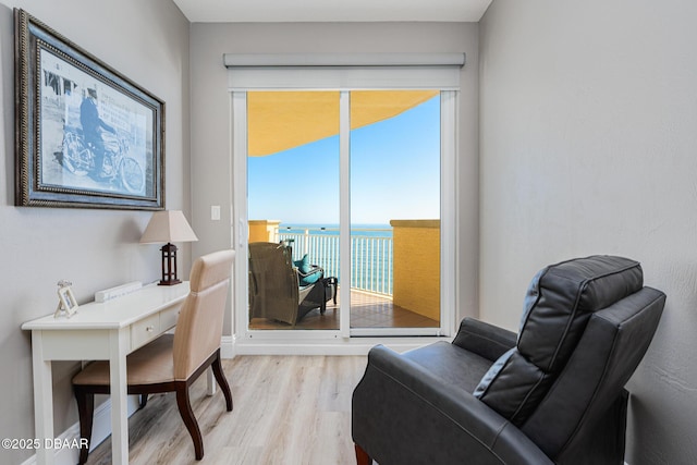 sitting room featuring a water view and light wood-type flooring