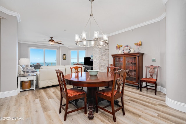 dining area with crown molding, ceiling fan with notable chandelier, and light wood-type flooring