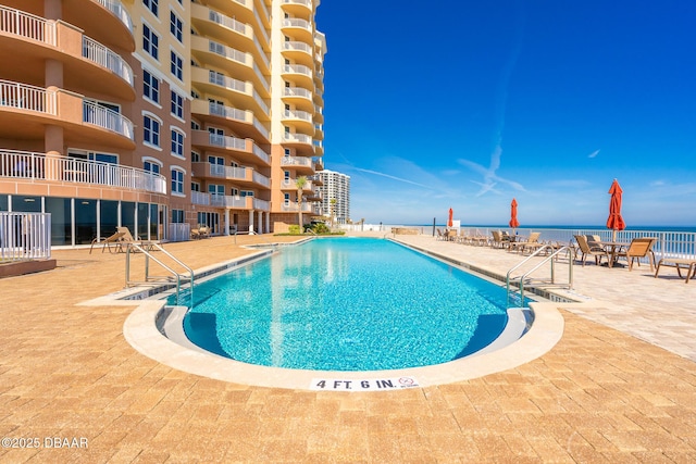 view of pool featuring a patio area and a water view