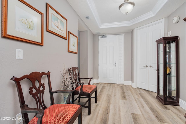 foyer entrance featuring crown molding, a tray ceiling, and light hardwood / wood-style floors