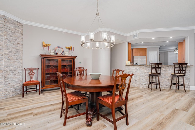 dining space featuring crown molding, light hardwood / wood-style flooring, and a notable chandelier