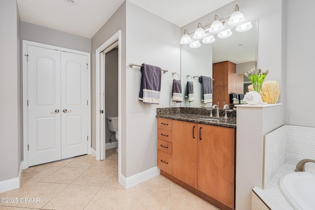 bathroom with tile patterned floors, toilet, a bath, and vanity