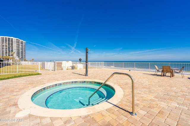 view of swimming pool featuring a hot tub, a patio, and a water view