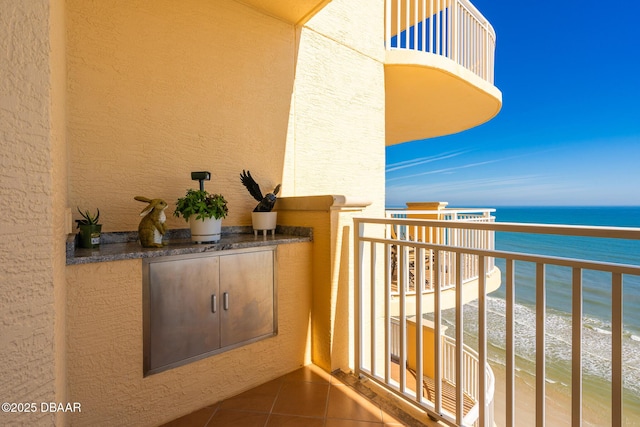 balcony with a water view, area for grilling, and a view of the beach