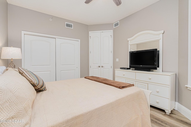 bedroom featuring ceiling fan, two closets, and light wood-type flooring