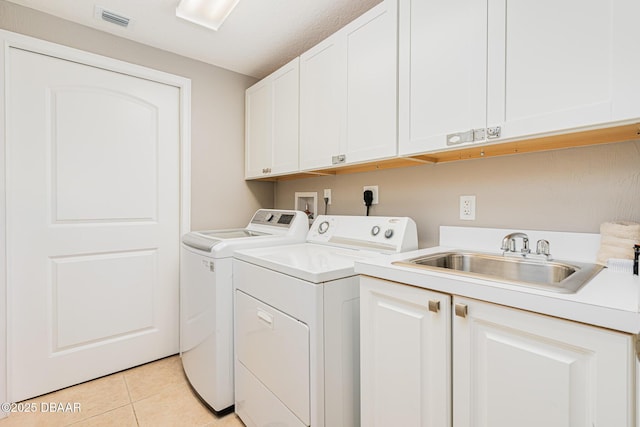 clothes washing area featuring cabinets, separate washer and dryer, sink, and light tile patterned floors